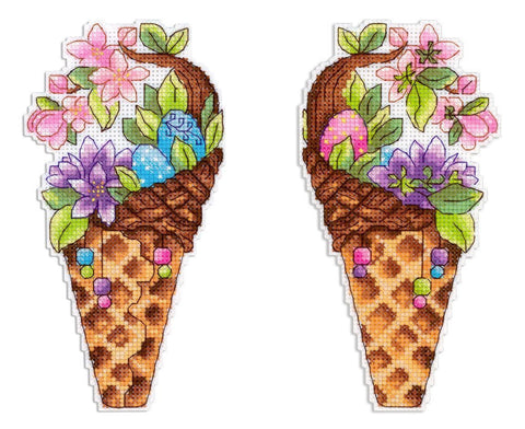 Siuvinėtas ženkliukas – lelijos ir pastelinių kiaušinių kompozicija rudiame pintame krepšelyje, matomos dvi variacijos (mėlynas ir rožinis kiaušinis)