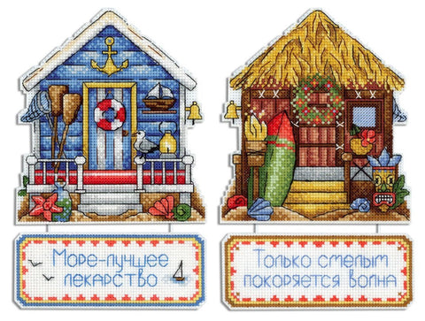 Siuvinėjimo rinkinys su dviem pajūrio nameliais — mėlynu gelbėjimo kotedžu ir šiaudine trobele, abi su dekoratyvinėmis lentelėmis