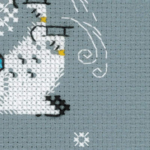 Siuvinėjimo rinkinys – arti pilko Aida audinio fragmentas su baltu sniego žmogaus kryželiu, mėlyna akimi ir baltomis spiralėmis