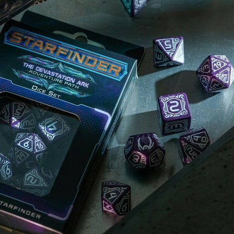 Starfinder kauliukai purpuriniai poliedriniai rinkinys, dėžutėje ir išbarstyti ant metalinio stalo su kampiniu apšvietimu