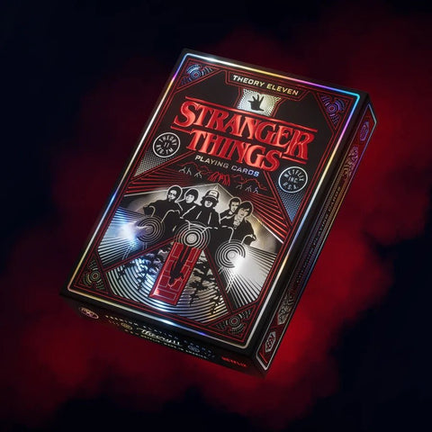 Stranger Things žaidimo kortos su raudonai‑juodu metalizuotu dėklu ir reljefuotu retro dizainu, kampu nufotografuota kolekcinei versijai