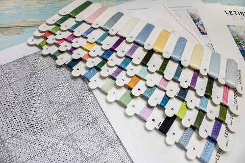 Siuvinėjimo siūlai su spalvų kortele ir simbolių schema, aiškiai rodantys komplekto atspalvius ir žymenis