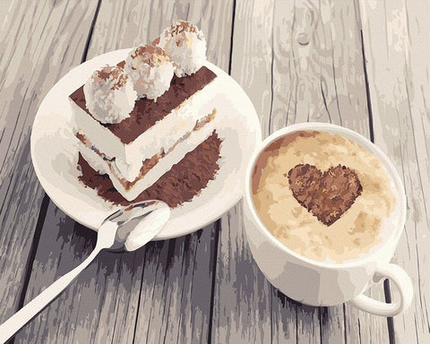 Kava latte baltoje puodelyje su širdies formos kakavos pabarstymu ant putos, patiekiama šalia tiramisu gabalėlio ant medinio stalo