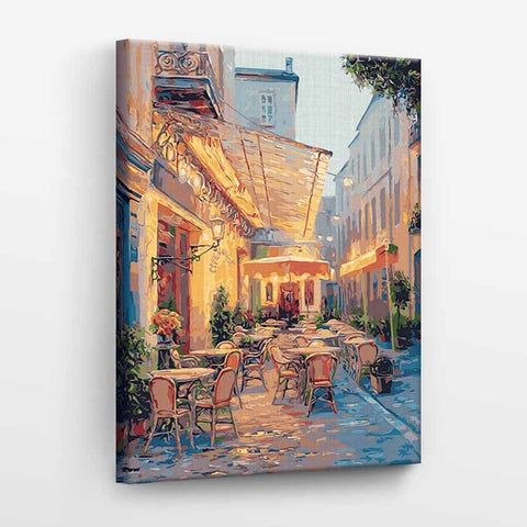 Drobė su spalvota kavinės terasos tapyba, šiltų tonų 60×90 cm variantas, rodoma iš šiek tiek šoninio kampo