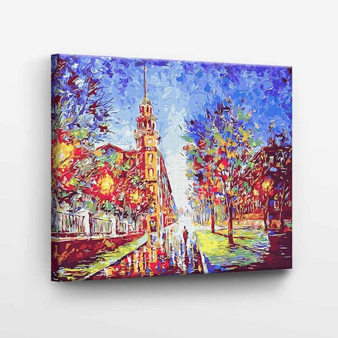 Drobė spalvinga miesto gatvės tapyba 60×40 cm, rodoma kampu su aukštu bokštu ir medžių atspindžiais šlapiame asfalte
