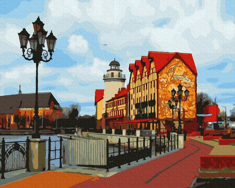 Drobė 60×40 cm su ryškiais raudonais ir aukso tonais, panoraminis uostamiesčio prieplaukos ir švyturio motyvas interjerui