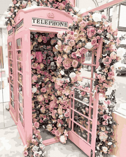 Dekoratyvinė rožinė telefonų būdelė, užpildyta gausiu rožių vijokliu ir atidarytom durim, skirta fotosesijoms ir vitrinos dekorui
