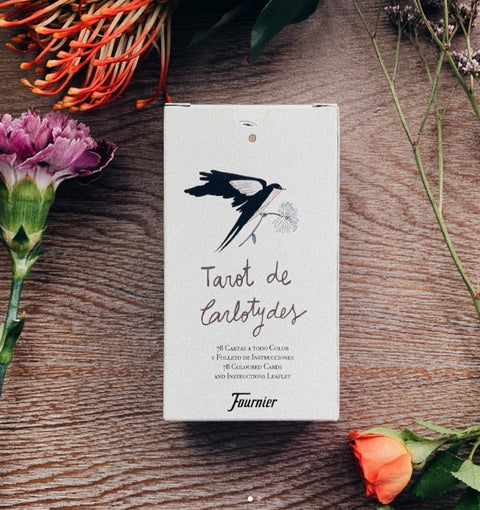 tarot kortos Fournier baltoje dėžutėje su kregždės piešiniu, 78 kortos, ant medinio stalo, apsuptos gėlių