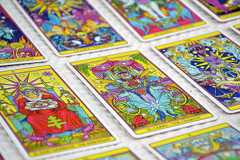 Tarot kortos ryškus psichodelinis komplektas išdėstytas plokščiai, artimas kampinis kadras akcentuoja kortų detales ir simboliką
