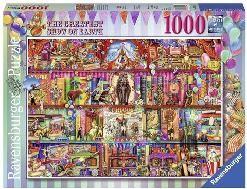 1000 detalių dėlionė Ravensburger, ryškios cirko scenos iliustracijos ant dėžutės priekinės, pabrėžianti pilną piešinio kompoziciją