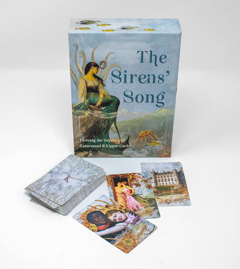 Kortų rinkinys The Sirens' Song su šviesiai mėlynu dėklu ir trimis atvertomis Lenormand–Kipper kortomis ant balto fono
