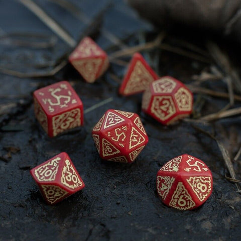 RPG kauliukai raudoni 7 dalių metalizuotas rinkinys su auksiniais skaitmenimis, arti sufokusuoti ant tamsaus natūralaus fono