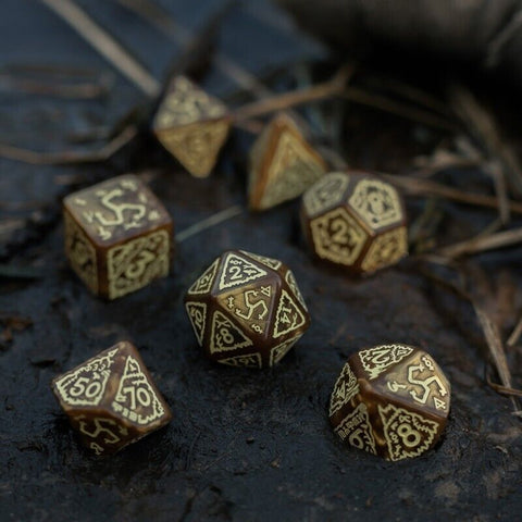 RPG kauliukai rudos su auksiniais graviravimais, 7 dalių rinkinys ant tekstūruotos tamsios paviršiaus, artimas planas