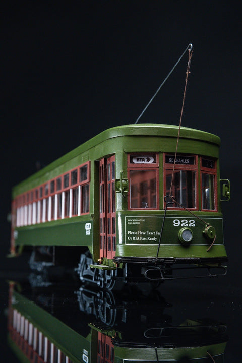 Modelinis tramvajus žalias–raudonas, priekinis kampinis iš arti, matomas blizgaus paviršiaus atspindyje