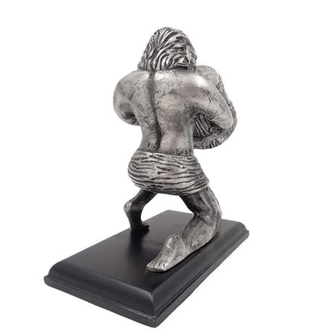 Skulptūra sidabrinė kario figūra ant juodo stačiakampio pado, nugarinis žvilgsnis pabrėžia raumenų ir audinio faktūrą