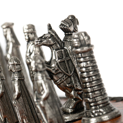 Šachmatų rinkinys su žalvario spalvos metaline raitelio figūra ir bokštu, arti sufokusuotas makro kadras