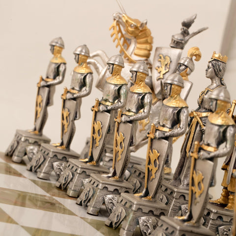 šachmatų figūrėlės sidabro ir aukso spalvų, artiškas kampinis planas, akcentuojantis riterių šarvus, skydų raižinius ir marmuro lentą