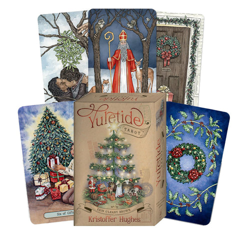 Tarot kortos Yuletide – kieta dėžutė su šventine eglute ir kelios iliustruotos kortos, parodytos fanuotai, komplektas