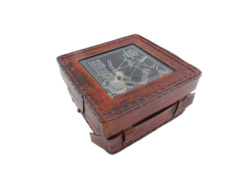 Odinė rudos spalvos stačiakampė dėžutė su permatomu dangčiu ir siūlių dekoru, kampinis vaizdas atskleidžia viduje esančią senovinę navigacijos priemonę