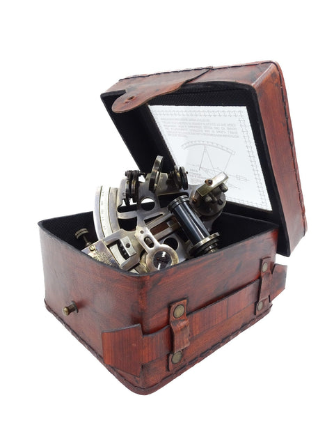 Sextantas rudos odinės dėžutės viduje, kompaktiškas metalinis navigacijos prietaisas su atidarytu dangčiu ir instrukcija kambarinio kampo fotografijoje