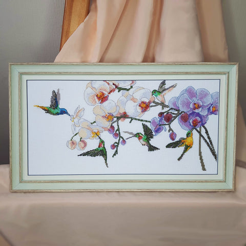 Rankų siuvinėtas stačiakampis paveikslas su violetinėmis orchidėjomis ir spalvingais kolibriais, žalsvas rėmas, priekinis vaizdas ant satino