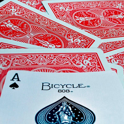 Kortos Bicycle 808 su raudonomis nugarėlėmis, arti fotografuotas pikų tūzas (A) priekyje, pabrėžia aukštą kokybę ir tekstūrą