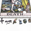Dėlionė „Death“ teminė artimas kadras, matomi unikalūs mediniai formos gabalėliai – kardas, šuo, papūga, kaukolė