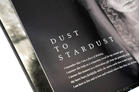Knyga su juodu puslapiu ir dideliu baltu užrašu Dust to Stardust, arti kampuotas interjero planas, pabrėžiantis vidinę antraštę