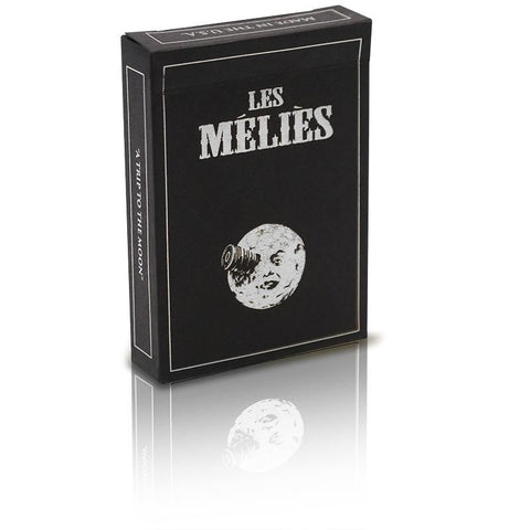 Kortų rinkinys Les Méliès juodo dizaino dėžutė su mėnulio iliustracija ir šonine „A Trip to the Moon“ užrašu, pasvirusiu kampu.