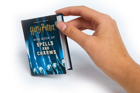 Mini knygutė Harry Potter — tamsiai mėlynas „Spells and Charms“ leidimas, parodytas rankoje, matomas viršelis ir knygutės storis