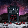 Stalo žaidimų kauliukai Space — juodi su raudonais kosminiais simboliais, komplekte pakuotėje ant mėnulio paviršiaus