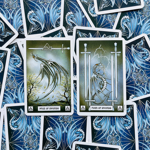 Tarot kortos su žaliai mėlynu drakono dizainu, dvi atverstos kortos (Page of Swords ir Four of Swords) plokščiai išdėstytos
