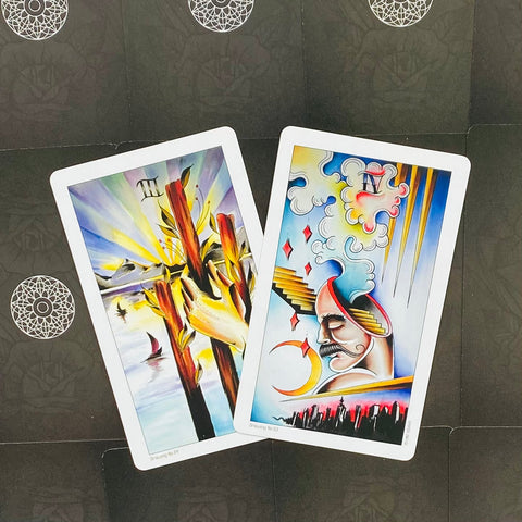 Tarot kortos dviejų spalvingų iliustracijų – rankų laikomos lazdos ir profilio figūra ant tamsaus, raštuoto fono, šiek tiek kampu