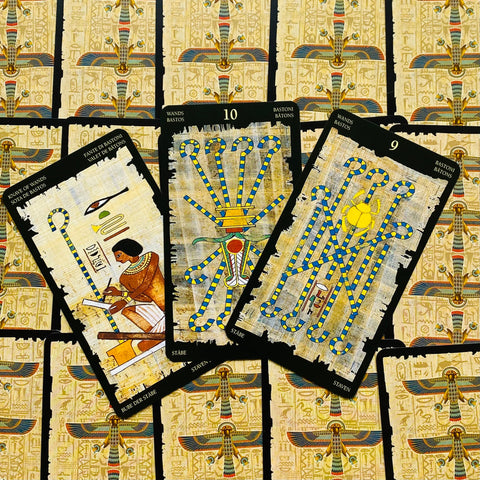 Tarot kaladė su egiptietiškais raštais — trys atverstos Lazdų kortos (tarp jų 9 ir 10) ant raštuotų nugarėlių fono