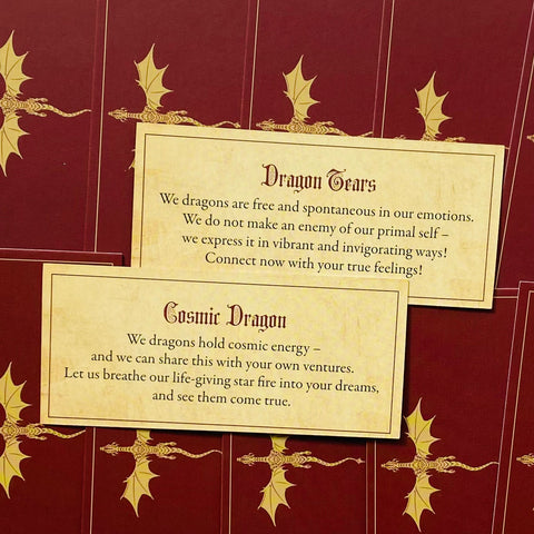 Orakulų kortos: raudonos su auksiniais drakonais, parodytos dvi kortos su „Dragon Tears“ ir „Cosmic Dragon“ tekstais