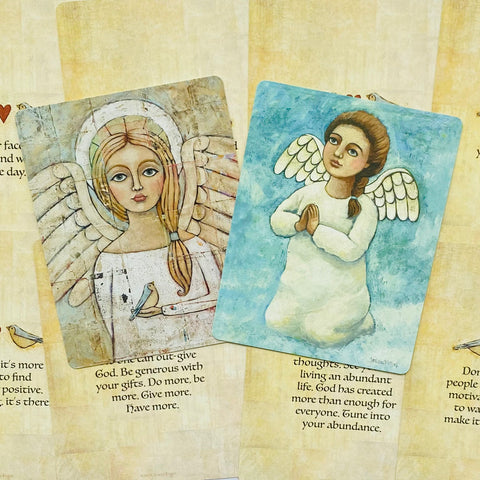 angelų kortos, rinkinys su smėlio ir melsvomis angeliukų iliustracijomis, parodytos nuo viršaus ant tekstinio fono