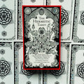 Hermetic Tarot kortų rinkinys: priekinė dėžutė su raudonu kraštu ir juodai baltu okultiniu piešiniu, išdėstyta ant kortų nugarėlių