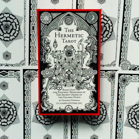Hermetic Tarot kortų rinkinys: priekinė dėžutė su raudonu kraštu ir juodai baltu okultiniu piešiniu, išdėstyta ant kortų nugarėlių