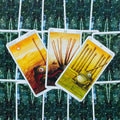 Tarot kortos — trys geltoni Lazdų rūšies kortos (9, 10 ir riteris) iš iliustruotos kaladės ant žvaigždėto žalio nugarėlių fono