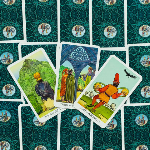 Tarot kortos RWS stiliaus: trys atidengtos monetų kortos (Two, Three, Four of Pentacles) ant žalsvai turkio nugarėlių