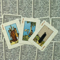 Tarot kortos Rider–Waite taurės: trys atvertos kortos (III, IV, V taurės) išdėstytos ant juodai baltų gėlių nugarėlių fono