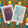 Tarot kortos su dviejų kardų kortomis, violetine ir melsva iliustracija, kampu persidengianti kompozicija