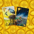 tarot kortos Little White Owl, dvi išskleistos kortos — 17 Gandras ir 16 Ratas, detaliai iliustruotos ant geltono galinio fono