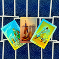 Tarot kortos Rider–Waite: trys kardų kortos išskleistos fanu, matomi 5, 6 ir 7 variantai ant mėlyno nugarėlių fono