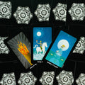Tarot kortos centre ant juodo mandalos fono, trys spalvotos kortos su liepsna, baltu žirgu ir taurės motyvu