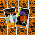 Tarot kortos su oranžinėmis‑juodomis katės nugarėlėmis, dvi atverstos kortos (Two of Bats ir Ace of Bats) parodytos iš viršaus