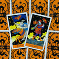 Tarot kortos su oranžinėmis nugarėlėmis ir juodu katės raštu — dvi atverstos kortos (Knight of Bats ir Page of Bats) matomos iš viršaus