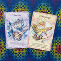 Oracle kortos: dvi priekinės kortos Healing (mėlynos tonacijos) ir Happiness (rožinės), padėtos ant spalvoto ornamentinio fono