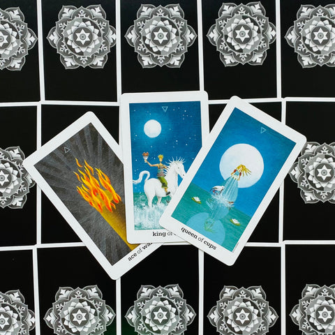 Tarot kortos — trys atverstos kortos (Ace of Wands, King of Cups, Queen of Cups) ant juodo mandalos fono, parodo kortų piešinius ir spalvų variantą