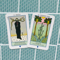 Tarot kortos, dvi atverstos kortos Death ir Hanged Man su ryškiais piešiniais ant žalsvai raštuotų nugarėlių, matomas priekinis kortelių paviršius